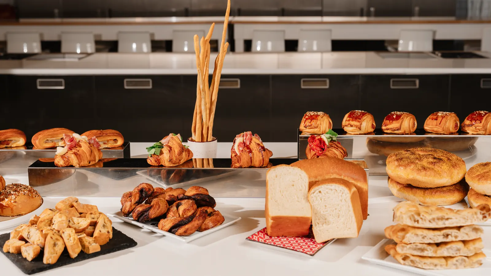 Banco del laboratorio ReD con pan bauletto, focacce, treccine al cacao, croissant salati e grissini