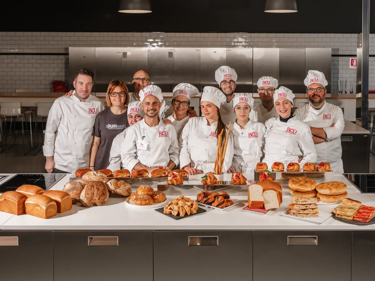 Docenti e allievi in divisa ReD dietro il banco con pane, focacce e viennoiserie