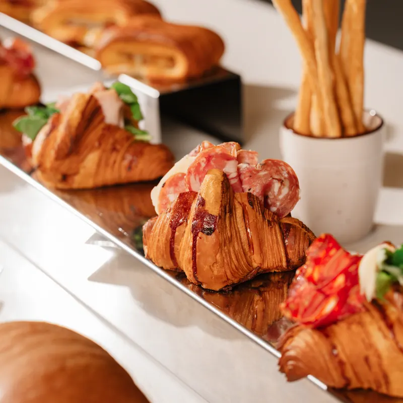 Croissant salati farciti con salumi e insalata, con i grissini sullo sfondo