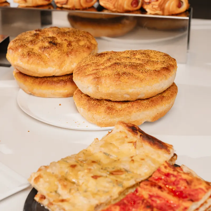 Focacce tonde impilate e tranci di pizza in teglia bianca e rossa