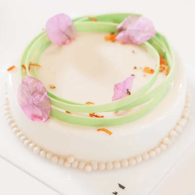 Torta con glassa bianca, cerchi verdi e petali