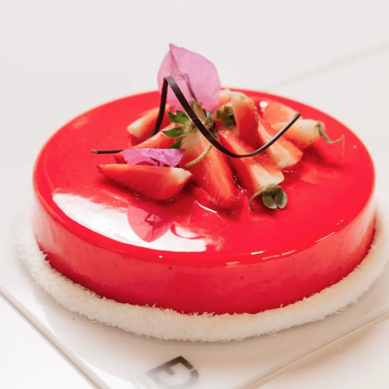 Torta con glassa rossa a specchio, fragole fresche e cocco