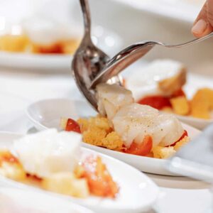 finger food in preparazione con pesce e pomodori in piccoli piatti bianchi