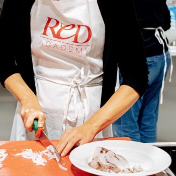 ragazza pulisce il pesce durante il corso amatoriale di cucina