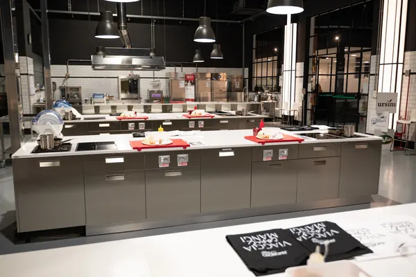 Le isole di lavoro preparate con taglieri, piatti e grembiuli prima dell'arrivo del gruppo