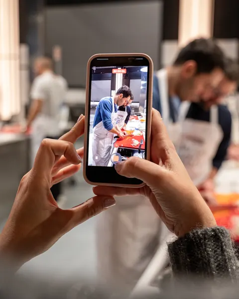 Una partecipante riprende con il telefono un collega che taglia le verdure